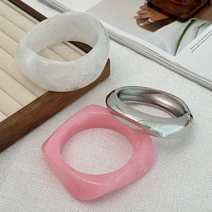 Detail of marble resin and polished silver metal bangles set on a display tray