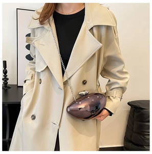Detail of egg-shaped metallic clutch with silver chain strap shown on cream coat