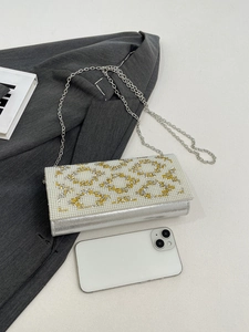 Detailed macro of silver glossy clutch with pearl rhinestone pattern on a suit jacket