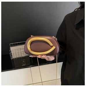 Detail der burgunderroten Leder-Clutch mit goldenem C-Griff und feiner Kettenriemen