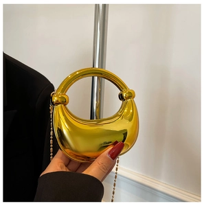 Detail einer goldenen sichelförmigen Handtasche mit Spiegeleffekt und rundem Griff