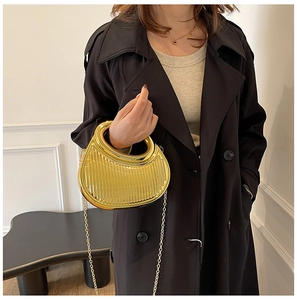 Close-up of golden metallic handbag featuring vertical ridges and a round handle detail