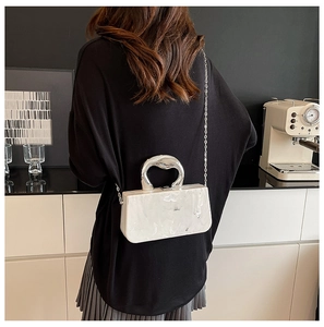 Détail du sac boîte en acrylique marbre blanc avec poignée en métal argenté