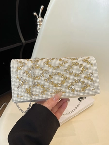 Macro detail of white faux pearls and geometric crystal inlay on elegant evening bag