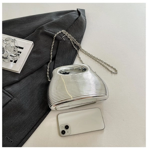 Macro view of silver metallic ribbed handbag with chain and hollow handle on grey blazer