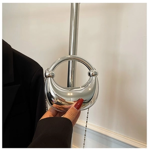 Detail der metallischen Halbmondtasche mit Rundgriff und abnehmbarer Perlenkette