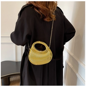 Detail of gold geometric handbag with vertical stripes and oval handle in a modern setting
