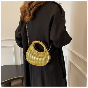 Macro detail of metallic gold pleated handbag featuring a circular handle and gold chain strap