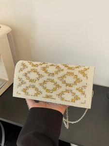 Detail of luxury pearl evening clutch bag with geometric rhinestone patterns and chain