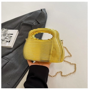 Detail of gold metal evening bag with hollow wave texture and elegant chain strap