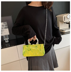Vue détaillée du sac de soirée en acrylique marbré jaune et vert avec poignée en métal en U