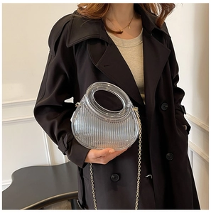 Close-up of transparent acrylic handbag with vertical stripes and golden chain strap