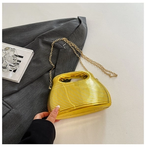 Detail view of the gold textured ripples on a metallic evening bag with a gold chain strap