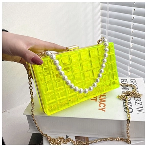 Détail du sac à bandoulière en acrylique jaune fluo avec poignée en perles et chaîne dorée
