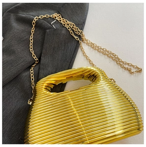 Detail of gold evening clutch with wavy texture and gold chain on gray blazer