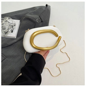 Detail der weißen kieselsteinförmigen Clutch mit klobigem goldnem C-Griff und Kette