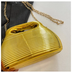 Close-up of gold evening bag with horizontal ripple texture and sleek metal chain