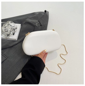 Detail der weißen halbrunden Clutch mit eleganter Goldkette und mattem Oberflächenfinish