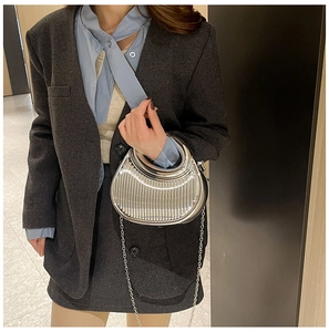 Detail of silver pleated handbag with metallic ring handle and detachable chain strap