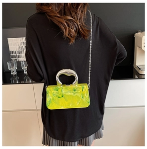 Détail de la pochette en acrylique marbré vert avec grande poignée argentée et chaîne