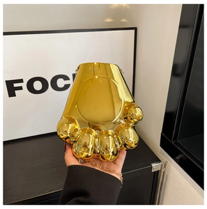 Détails d'un sac de soirée doré brillant en forme de patte avec bandoulière chaîne