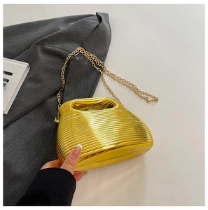 Detail of gold pleated evening bag with high-shine metallic texture and handle