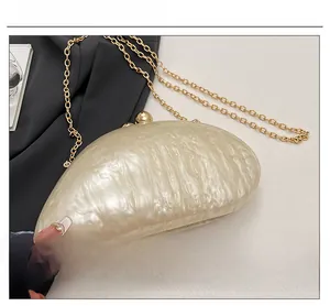 Macro detail of acrylic evening bag with mother-of-pearl texture and gold ball clasp