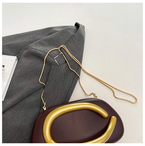 Detailansicht der weinroten Abendtasche mit goldener C-Schnalle und Schlangenkette