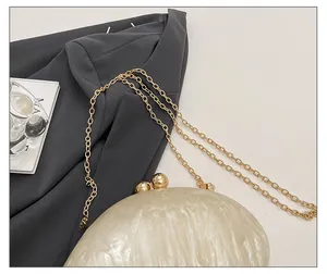 Close-up of golden chain strap and marble textured acrylic evening clutch surface