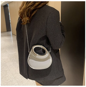 Silver metallic pleated handbag with circular handle and chain strap shown on model