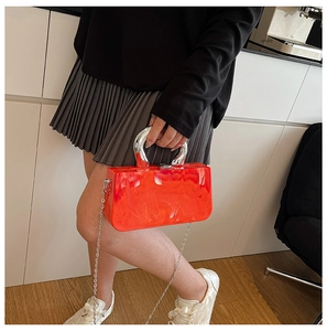 Détail du sac boîte en acrylique orange marbré avec poignée en métal argenté et chaîne