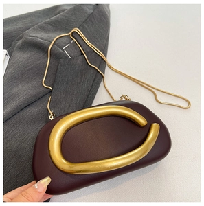 Detail der burgunderroten Abendtasche mit goldener C-Schließe und edler Schlangenkette
