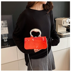 Détail du sac boîte en acrylique marbre rouge avec poignée argentée dans un café