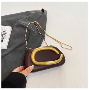 Details der burgunderroten Abendtasche mit goldenem Griff und feiner Schlangenkette