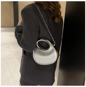 Detail of silver metallic crescent bag featuring pleated texture and round cutout handle