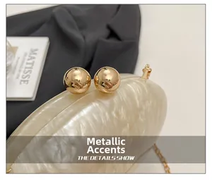 Macro view of gold spherical hardware clasp on marble pattern resin evening clutch bag