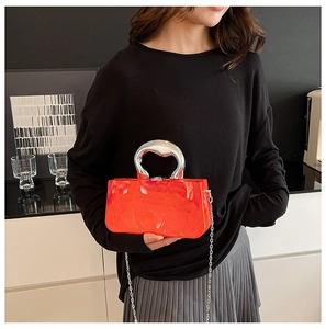 Détail du sac de soirée en acrylique marbré rouge avec poignée argentée sur modèle