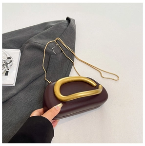 Nahaufnahme der weinroten Clutch mit goldenem Griff und eleganter Metallkette