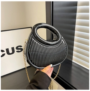 Detail of black glossy hobo bag featuring vertical pleats and circular hollow handle