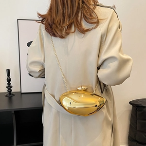 Polished gold mirror metallic clutch bag with chain strap on a model in beige coat