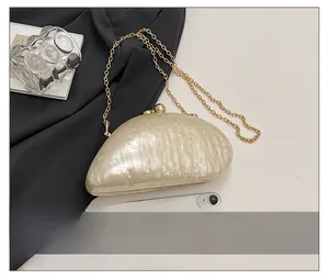 Detail view of pearlescent evening clutch with gold chain showing size relative to a phone