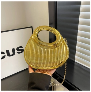 Macro detail of the gold metallic handbag showing vertical pleated texture and ring handle