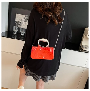 Détail du sac boîte en acrylique marbré rouge-orange avec poignée argentée et chaîne