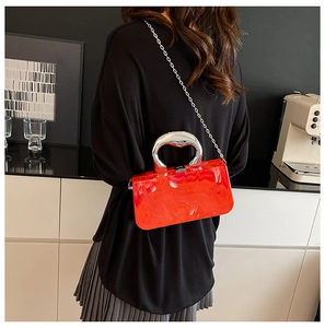Petit sac rouge à motif marbré avec poignée argentée porté par un mannequin