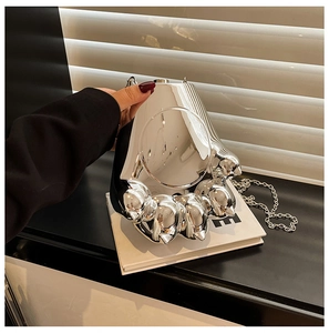 Détail du sac à main argenté en forme de patte de chat avec finition miroir et chaîne fine