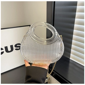 Detail of transparent acrylic handbag with vertical ridges and gold metal chain strap