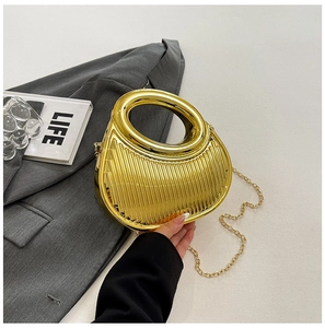 Detail of metallic gold pleated handbag with integrated circular handle and chain strap