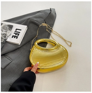 Detail shot of a semi-circular gold metal evening bag with vertical pleated texture