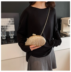 Detail of marble acrylic evening clutch with gold chain and ball clasp on a table