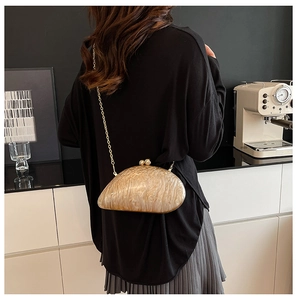 Detail of marble pattern acrylic evening clutch with gold chain and irregular pebble shape
